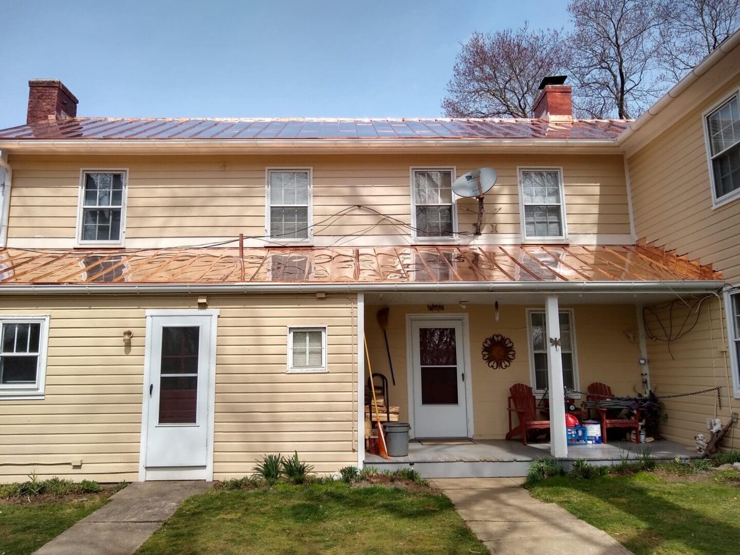 Shiny standing seam copper roof on yellow farmhouse